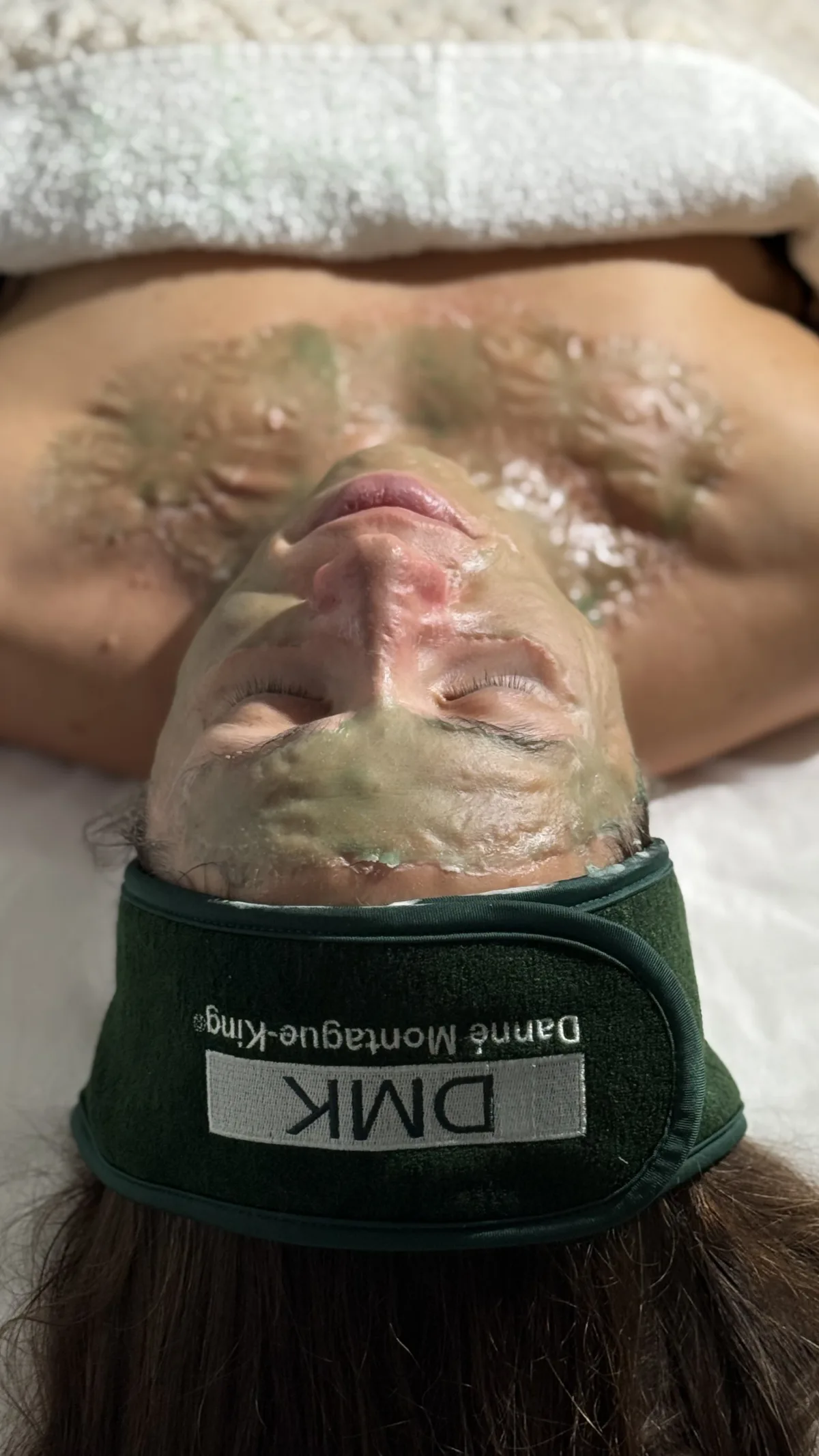 Client resting with a firm DMK masque across the face and upper chest